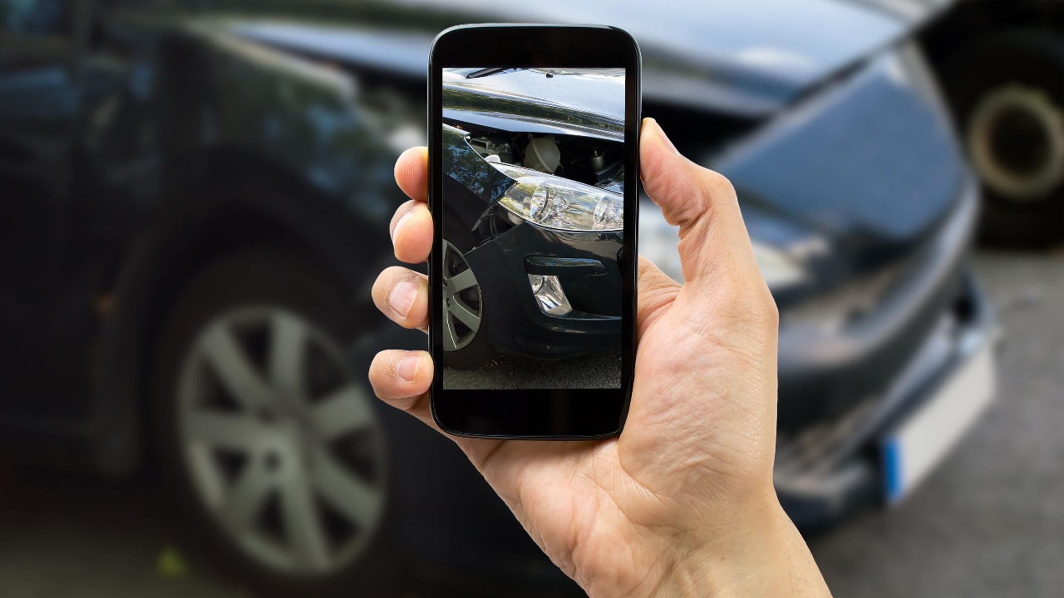 Mand fotograferer skader på bil med sin mobil.